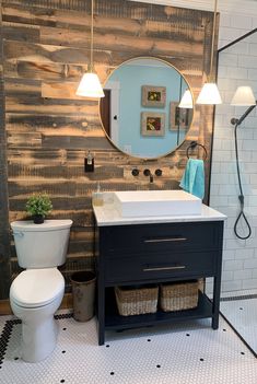 a white toilet sitting next to a sink in a bathroom under a large round mirror