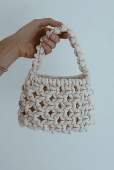 a hand holding a crocheted white purse