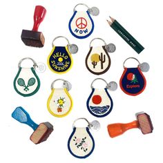 a group of different colored key chains with badges and pencils in them on a white surface