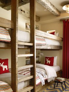 two bunk beds with red pillows in a room that looks like it has been made out of wood