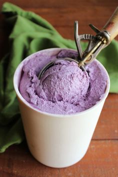 a cup filled with purple ice cream on top of a wooden table