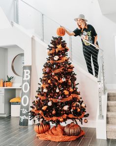 a woman standing on top of a stair case next to a christmas tree with decorations