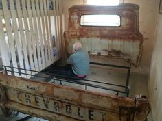 an old man is sitting on the bed frame in his home made out of wood and metal