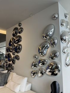 a living room filled with white furniture and lots of mirrors on the wall above it