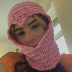 a woman wearing a pink crocheted scarf with a hood on her head and nose