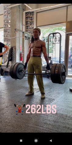 a man with no shirt is holding a barbell in the middle of a gym