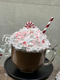 a cup filled with whipped cream and candy canes on top of a black plate