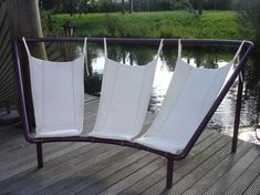 four white chairs sitting on top of a wooden deck next to a body of water