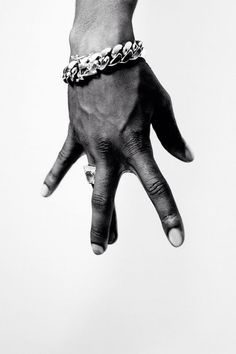 a person's hand with a chain bracelet on it, against a white background