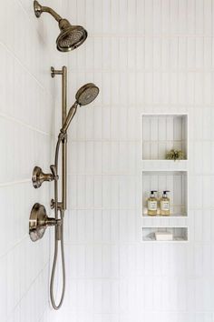 the shower head and handset are connected to the wall in this white tiled bathroom