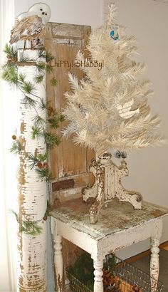 a small white christmas tree sitting on top of a table next to a wooden door