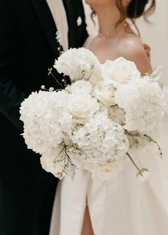 a bride and groom kissing in front of white flowers