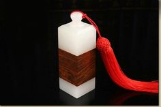 a white bottle with a red tassel is on a black surface next to a dark background