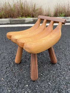 a wooden bench sitting on top of a parking lot next to a grass covered field