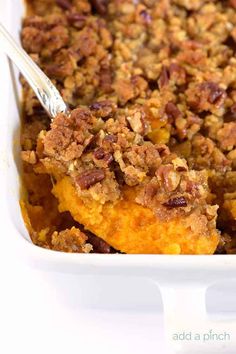 a casserole dish filled with sweet potatoes and crumbled pecans on top