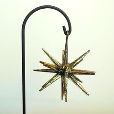 a metal star ornament hanging from a black pole on a white wall background