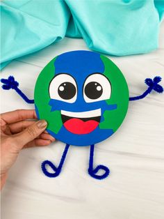 someone is holding up a paper plate with the earth on it's face and arms