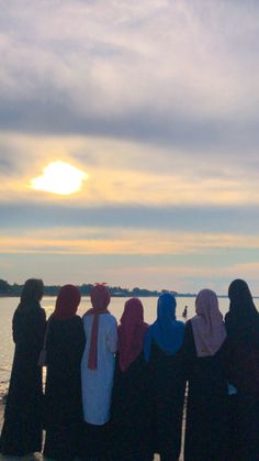 a group of women standing next to each other near the ocean