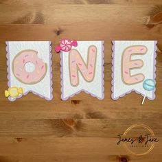 a wooden table topped with pink frosted donuts and lollipops on top of it