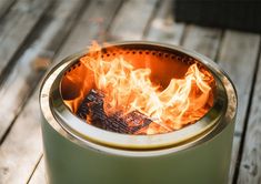 a fire pit sitting on top of a wooden table next to a green pot filled with flames