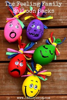 four painted eggs with faces on them sitting on top of a wooden table next to each other