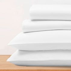 three white pillows stacked on top of each other in front of a light wood table