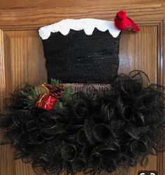 a black wreath with a red bird on it and a christmas stocking hanging from the front door