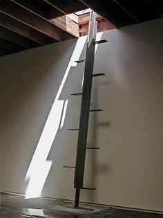 a tall metal pole sitting in the middle of a room next to a white wall