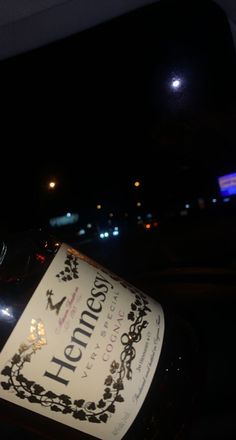 a bottle of wine sitting on the hood of a car in the dark at night