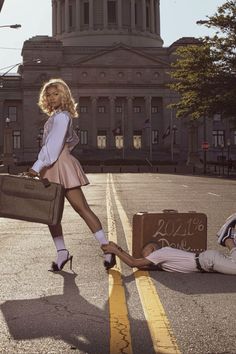 a woman in a short skirt and heels standing next to a man laying on the ground