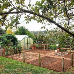 a garden area with a fence, potted plants and a small building in the background