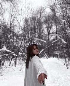 a woman standing in the snow pointing at something