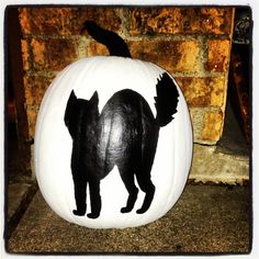 a black cat painted on a white pumpkin