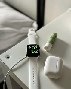 an apple watch sitting on top of a white table next to headphones and a charger