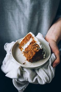 a person holding a plate with a piece of cake on it in their hands,