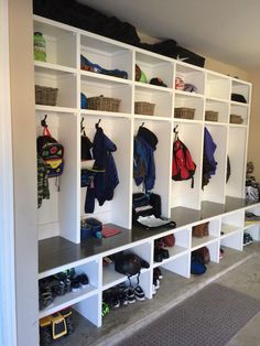 a room filled with lots of white shelves covered in coats and shoes on top of them