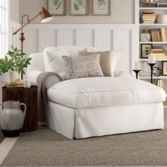 a white chaise lounge chair in a living room with bookshelves behind it