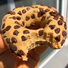 a half eaten chocolate chip doughnut in someone's hand