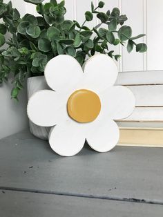 a white flower sitting on top of a table next to a potted plant