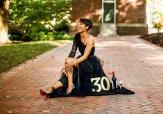 a woman sitting on top of a black dress next to a bottle of booze