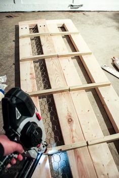 a person using a power drill to attach the sides of wooden planks with screwdrivers