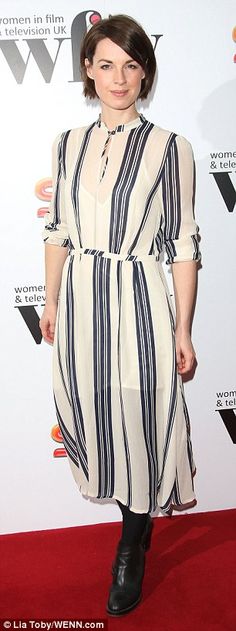 a woman standing on a red carpet wearing a white and blue dress with black stripes