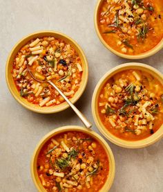 three bowls of soup with spoons on the side and one bowl filled with beans