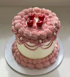 a pink cake with white frosting and cherries on top