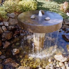 a water fountain surrounded by rocks in a garden