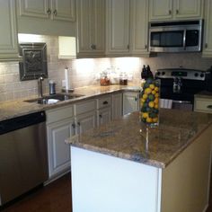 a kitchen with white cabinets and granite counter tops