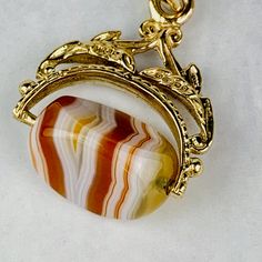 "This is a beautiful Victorian style Swivel Fob Seal / Pendant in 9K / 9ct yellow gold. The spinning fob pendant features hand carved floral gold design and a triangle shaped banded agate with vibrant white, red/orange, and yellow colors. The fob measures 0.87\" (22.3mm) high including bail without split ring and 0.76\" (19.4mm) wide at it is widest point. It is fully hallmarked for Birmingham Assay, 9ct gold, and year letter for 1977. It weighs 3.862 grams. All of our listings come in a box rea Yellow Gold Oval Agate Jewelry, Oval Agate Yellow Gold Jewelry, Oval Yellow Gold Agate Jewelry, Gold Cabochon Gemstones For Formal Occasions, Formal Gold Cabochon Gemstones, Classic Gold Gemstones With Polished Finish, Heirloom 14k Gold Gemstones, Classic Carnelian Yellow Gold Jewelry, Classic Yellow Gold Carnelian Jewelry