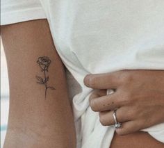 a woman with a rose tattoo on her left arm and the other hand behind her back