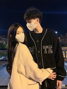 a man and woman standing next to each other wearing face masks