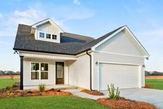 a white house with black roof and two garages